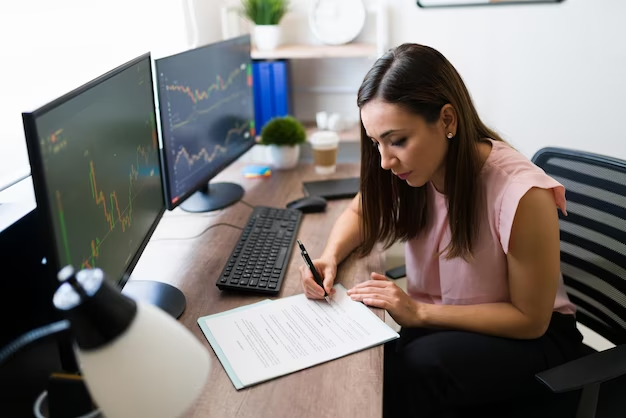 Businesswoman diligently keeping a trading journal, documenting trades, analyzing strategies, and reflecting on trading performance on the desktop screens.