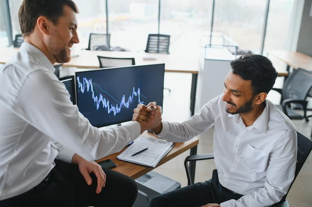Two successful traders sitting in their office, exuding a positive mindset as they analyze and monitor the financial markets on their screens.