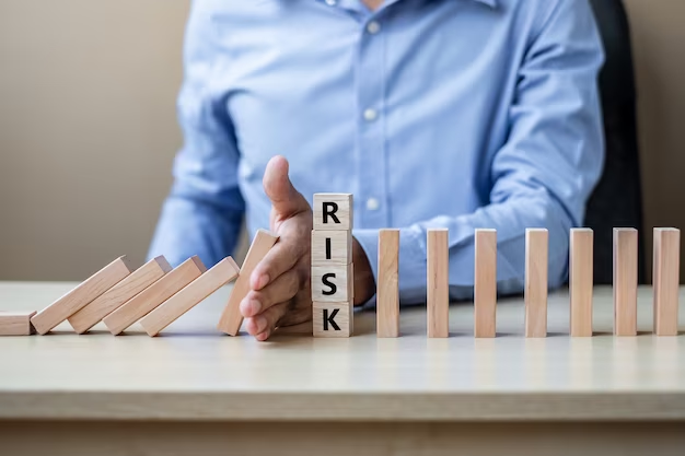 A businessman's hand stopping falling wooden blocks or dominoes, symbolizing prevention or intervention to avoid potential consequences or setbacks in business.