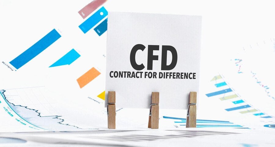 The image showcases the concept of Contract for Difference (CFD) with a paper sheet displaying the text "Contract for Difference." It is accompanied by various elements such as a chart, dice, spectacles, pen, and a laptop. 