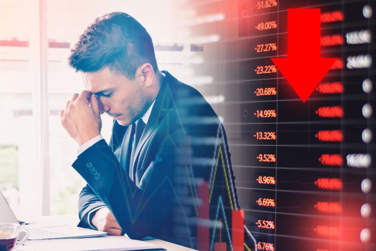 A trader exhibiting signs of distress while viewing a falling financial market chart, illustrating the risks of overleveraging in trading.
