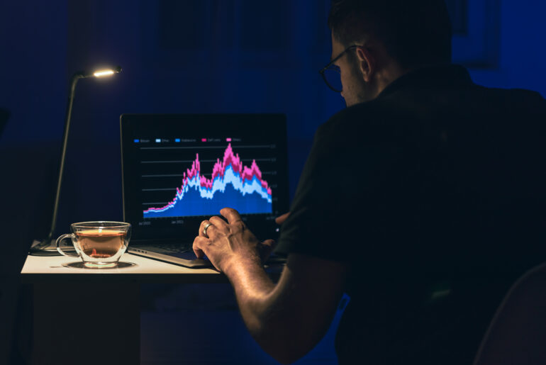 A professional trader analyzing technical analysis stock charts on a laptop in a dark room, focusing on market structure and liquidity zones.
