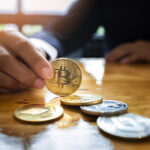 Close-up of a businesswoman holding a physical golden Bitcoin coin, representing Bitcoin's market share and its influence on altcoin trading strategies.