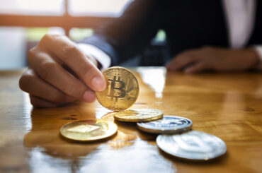 Close-up of a businesswoman holding a physical golden Bitcoin coin, representing Bitcoin's market share and its influence on altcoin trading strategies.