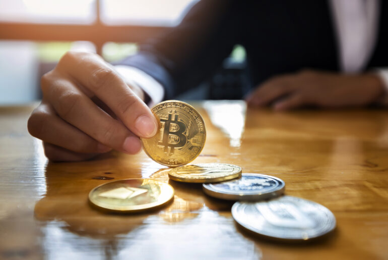 Close-up of a businesswoman holding a physical golden Bitcoin coin, representing Bitcoin's market share and its influence on altcoin trading strategies.