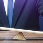 Businessman balancing red and green figures on a seesaw representing market imbalance and price rebalancing in Fair Value Gap trading