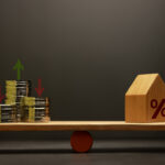 Stacked coins and house balanced on a seesaw scale with percentage symbol representing fixed lot vs percentage risk trading strategy.