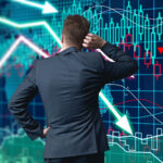 A businessman in a suit from behind, scratching his head while looking at a complex digital screen displaying fluctuating stock market candlestick charts and downward-pointing trend arrows.
