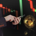 A double-exposure image of a professional in a dark blazer using a smartphone. In the background, a glowing red and green candlestick chart trends downward, while a large, physical-style gold Bitcoin coin floats in the foreground with a clear reflection.