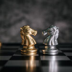 Two chess knights—one gold and one silver—facing each other on a chessboard, representing the strategic battle between internal and external liquidity in trading.