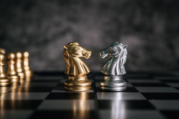 Two chess knights—one gold and one silver—facing each other on a chessboard, representing the strategic battle between internal and external liquidity in trading.