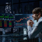 A professional trader analyzing live financial market charts and stock trends on multiple computer monitors at night, illustrating the concept of copy trading.