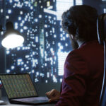 A financial analyst in a high-rise office examining crypto market charts and on-chain data metrics on a laptop at night.