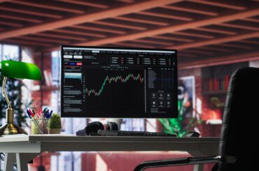 A modern trading station setup featuring a desktop monitor displaying financial charts and upward forex trends.