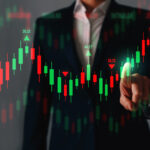 A trader pointing at an interactive forex financial candlestick chart showing green and red price movements.