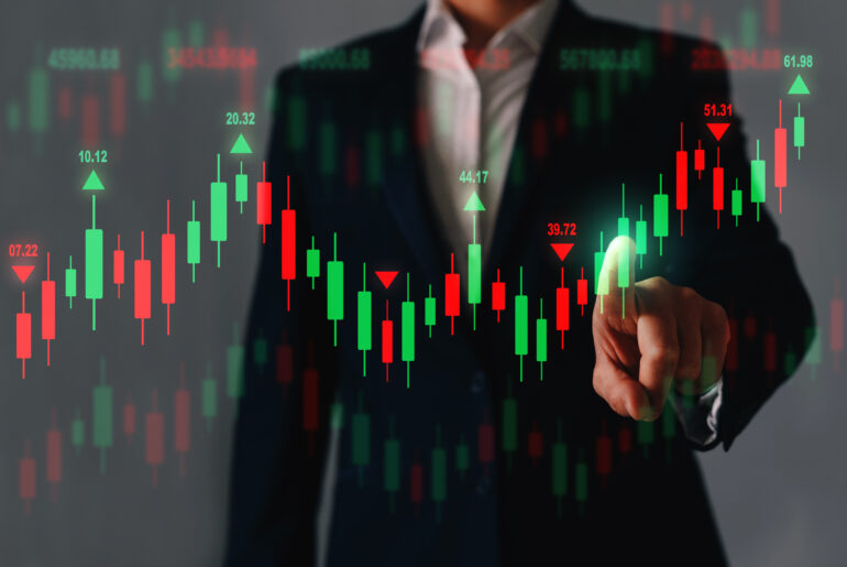 A trader pointing at an interactive forex financial candlestick chart showing green and red price movements.