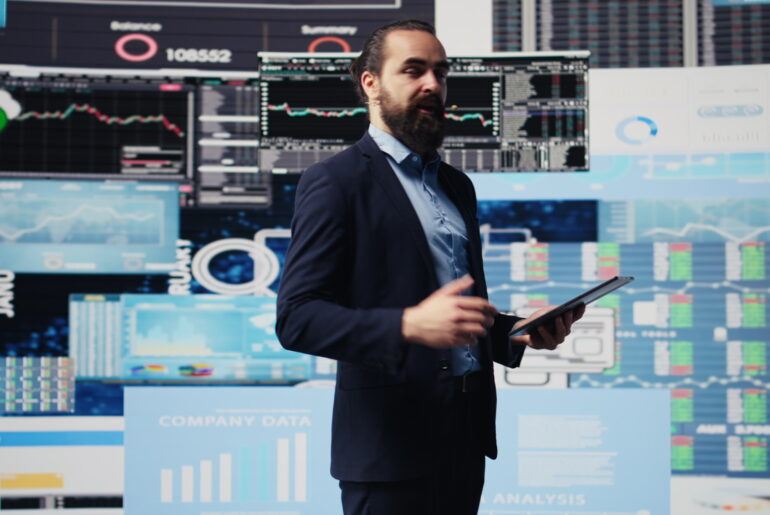 Professional trader presenting best strategies for commodity trading with market data and charts on display screens