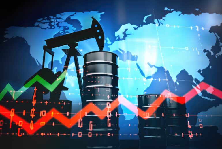 An oil pump jack and crude oil barrels set against a world map overlay with financial market line graphs representing Brent Crude Oil vs WTI price movements.