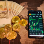 Physical fiat currency cash notes alongside crypto coins and a smartphone displaying a digital asset trading chart on a world map background.