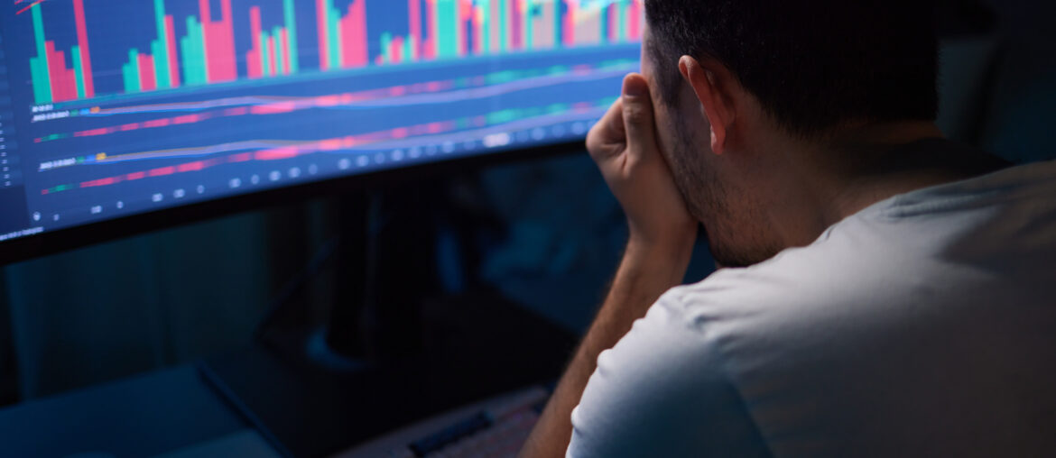 Trader analysing market sentiment and price charts showing fear and volatility on a trading monitor screen.