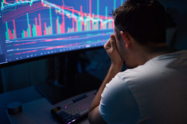 Trader analysing market sentiment and price charts showing fear and volatility on a trading monitor screen.